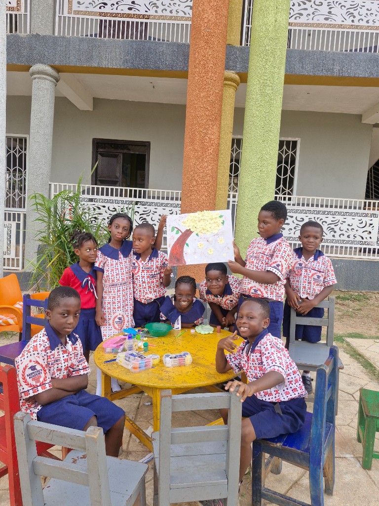 Primary pupils holding a handcrafted rooster sculpture outside the campus